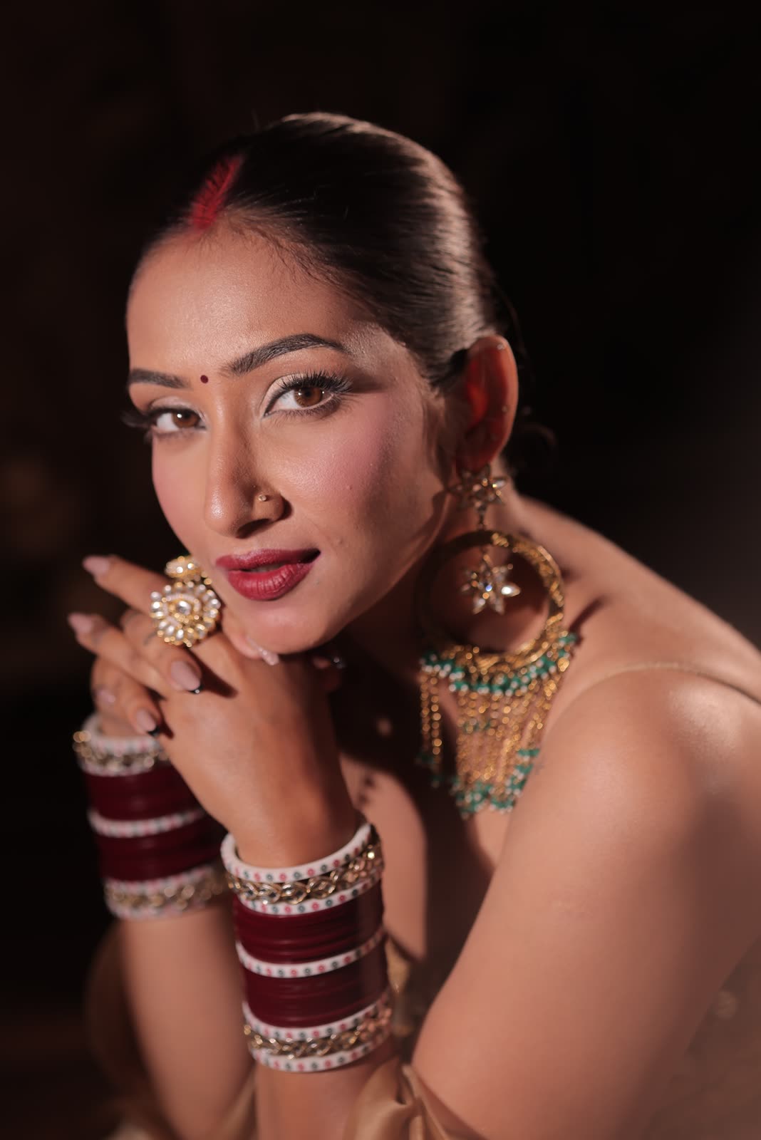 Portrait with a gold chandbali earring and maroon chura bangles